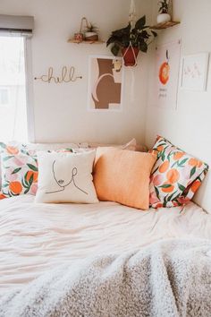 a white bed topped with lots of pillows next to a wall mounted plant and window