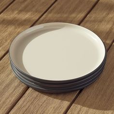 four plates stacked on top of each other on a wooden table with shadows from them