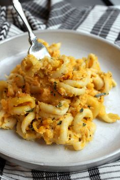 a white plate topped with macaroni and cheese on top of a checkered table cloth