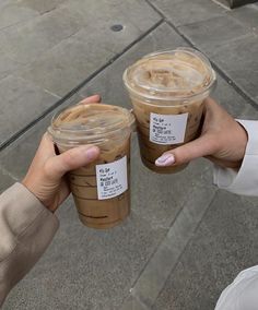 two people holding up cups of iced coffee