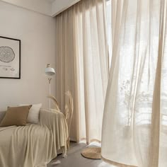 a living room filled with furniture and a window covered in white sheer curtaining next to a lamp