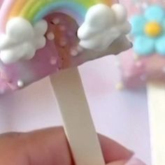 a hand holding a toothbrush with clouds and rainbows on it