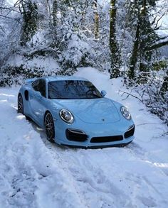 a blue sports car is parked on the side of a snow covered road in front of some trees