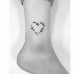 a heart shaped tattoo on the ankle with flowers and leaves in black ink is shown