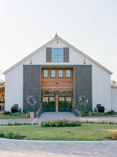 a large white barn with flowers and greenery on the front