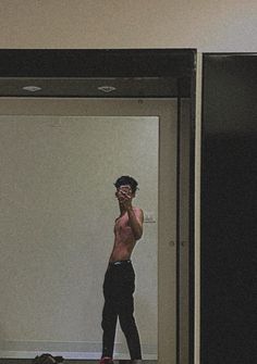 a shirtless man is taking a selfie in an elevator with his cell phone