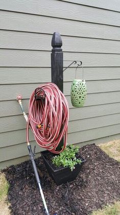 a garden hose is attached to the side of a house, next to a potted plant