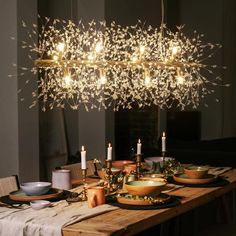 a wooden table topped with lots of plates and bowls next to a chandelier