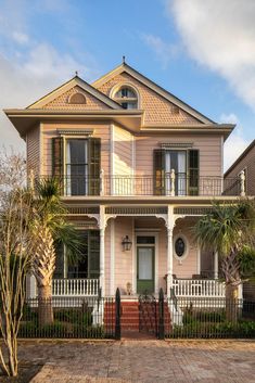 a large pink house with white picket fence and palm trees