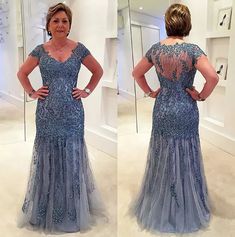 a woman in a blue dress is looking at herself in the mirror and she has her hands on her hips