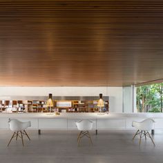 a long table with four chairs in front of it and a book shelf on the other side