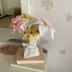 a white vase filled with pink and yellow flowers on top of a table next to a mirror