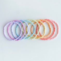 five different colored bracelets on a white surface