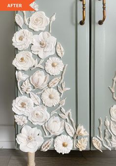 this is an art piece made out of paper flowers on a blue cabinet with gold handles