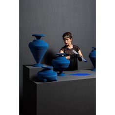 a woman is sitting in front of some blue vases