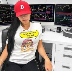 a woman sitting in front of two computer monitors wearing a t - shirt that says talk crypt to me