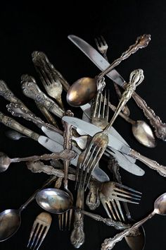 a bunch of forks and spoons are arranged in the shape of a star on a black background