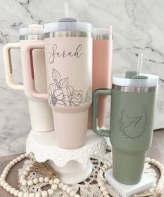 three different colored coffee mugs sitting on top of a doily next to each other