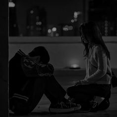 a woman sitting on the ground next to a man