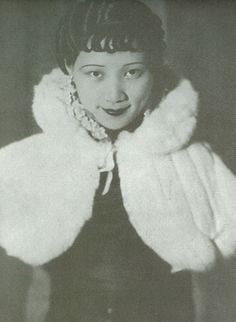 an old photo of a woman wearing a white fur coat and posing for the camera