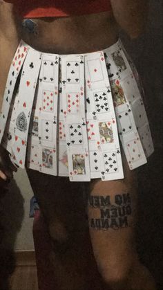 a woman wearing a skirt made out of playing cards with words written on the side