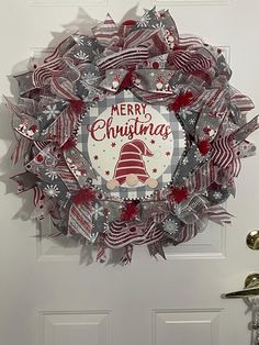 a christmas wreath hanging on the front door with merry christmas written in red and white