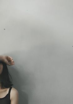 a woman standing in front of a wall with her hand on top of her head