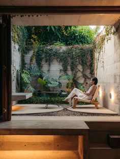 a man sitting on a chair in the middle of a room with lots of plants