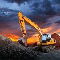 an excavator in the middle of a desert at sunset with dramatic clouds