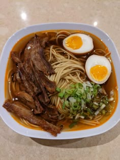 a bowl filled with noodles, meat and eggs