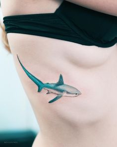 a woman's stomach with a shark tattoo on the side and under her belly