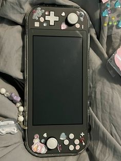 an electronic device is laying on a bed with buttons and beads around it's edges