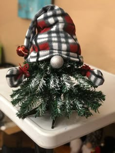 a small christmas tree is sitting on a white table with red and black plaid decorations