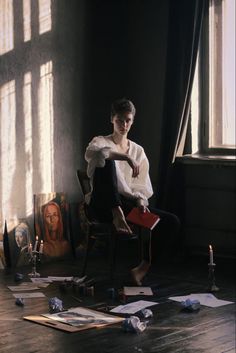 a young man sitting in a chair surrounded by papers and candles