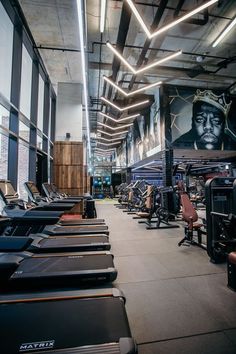 there are many treadmills lined up in the gym area with lights hanging from the ceiling