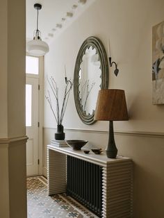 a room with a table, mirror and lamp on the sideboard in front of it