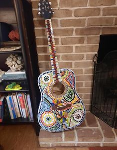 a colorful guitar sitting in front of a fireplace