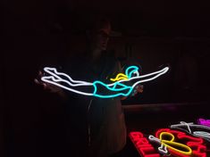 a man holding a neon sign in the dark