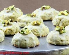 a tin filled with cookies covered in white frosting and pistachio toppings