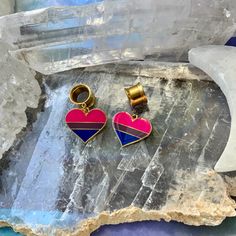 two heart shaped earrings sitting on top of a rock