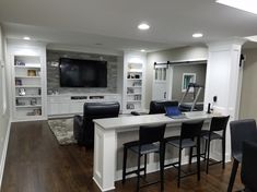 a living room filled with furniture and a flat screen tv mounted above a kitchen island