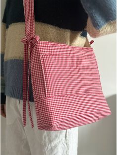 a woman holding a red and white checkered handbag in her right hand, with the back pocket open