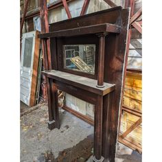 an old wooden table with a mirror on it in front of some other wood and metal items