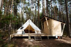 a tent in the woods with stairs leading up to it's roof and windows