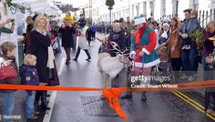 a group of people standing on the side of a road next to an orange ribbon