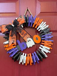 a halloween wreath made out of popsicle sticks and paper machs on a red door