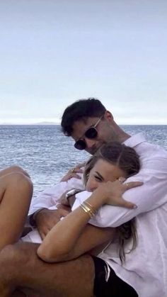 a man and woman sitting next to each other on a boat in the ocean with their arms around each other