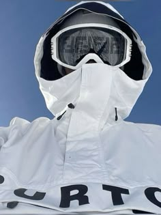 a snowboarder wearing goggles and a white jacket with the word burton written on it