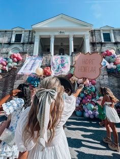 a group of girls standing in front of a building with balloons and a sign that says hope beneath