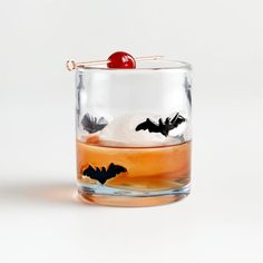 a glass filled with liquid and a cherry on the top in front of a white background